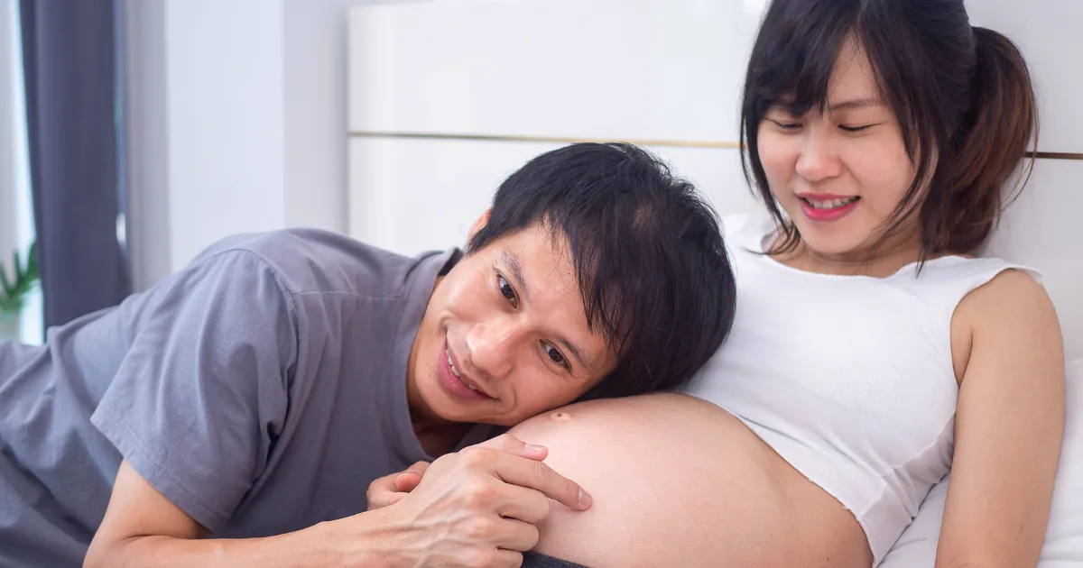 お腹に触れながら赤ちゃんに話しかける両親